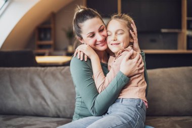 Happy mother and daughter enjoy spending time together at their home.