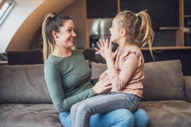 Happy mother and daughter enjoy spending time together at their home.