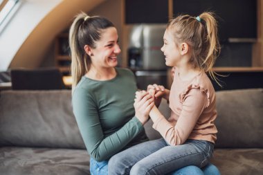 Happy mother and daughter enjoy spending time together at their home.