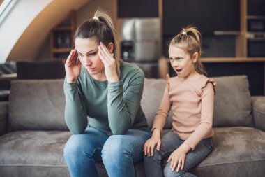 Stressed mother is  feeling desperate because of  screaming  her daughter.