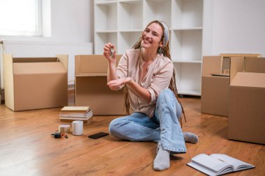 Yeni evinin anahtarını gösteren örgülü modern kızıl kadın..