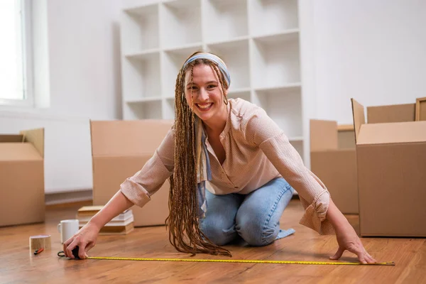 新しい家に移動し 床を測定するブレードを持つ現代ジンジャー女性 — ストック写真