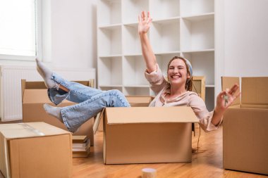 Mutlu kadın yeni evinin anahtarını kutuda oturmuş eğlenirken gösteriyor..