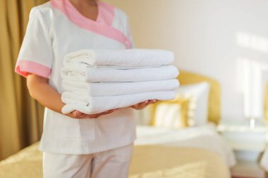 Otel hizmetçisinin temiz ve temiz havluları tuttuğu görüntüyü kapat..