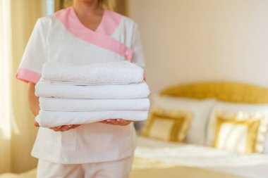 Otel hizmetçisinin temiz ve temiz havluları tuttuğu görüntüyü kapat..