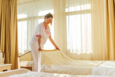 Güzel otel hizmetçisi bir odada yatak yapıyor..