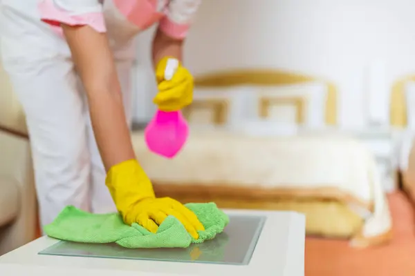 Close up image of  hotel maid cleaning table in a room.