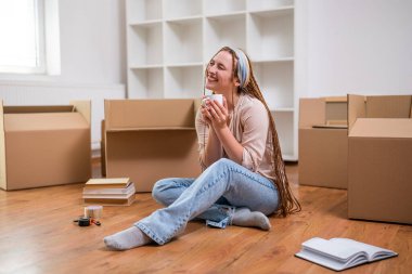 Yeni dairesine taşınırken saçı örgülü, kahve içen modern kızıl bir kadın..