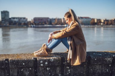 Nehrin kenarında oturan üzgün kadın. Tonu ayarlanmış resim.
