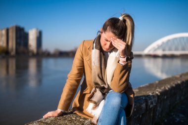 Nehir kenarında otururken baş ağrısı çeken endişeli bir kadın.. 