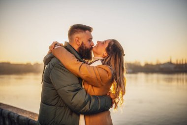 Mutlu çift gün batımında birlikte dışarıda vakit geçirmeyi sever. Adam kadınını çenesinden öpüyor..