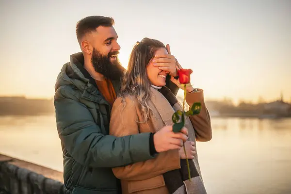 幸せな男は 彼の女性に赤いバラを与えながら 彼らは日没に一緒に時間を過ごすことを楽しんでいます — ストック写真