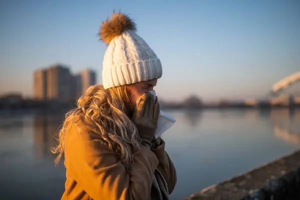 Nehrin Kenarında Otururken Sıcak Giysili Bir Kadın Burnunu Siliyor — Stok fotoğraf