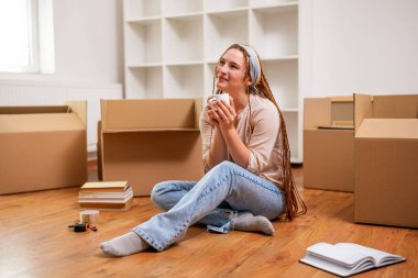 Yeni dairesine taşınırken saçı örgülü, kahve içen modern kızıl bir kadın..