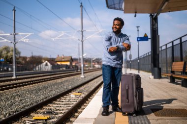 Tren istasyonunda duran bavullu mutlu adam..