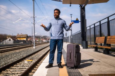 Tren istasyonunda duran bavullu kızgın adam..