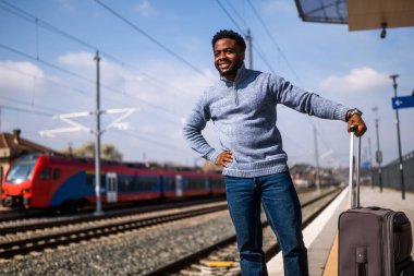 Tren istasyonunda duran bavullu mutlu adam..