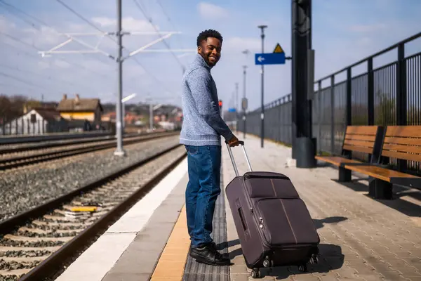 Tren istasyonunda duran bavullu mutlu adam..
