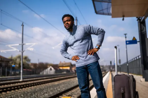 鉄道駅に立っているスーツケースを持つ心配な男 — ストック写真