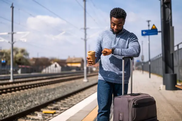Zmęczony Człowiek Patrzący Zegar Pijący Kawę Stojąc Walizką Dworcu Kolejowym — Zdjęcie stockowe