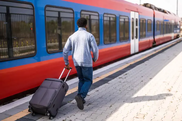 一个人背着手提箱沿着火车站奔向一辆离开的火车 — 图库照片
