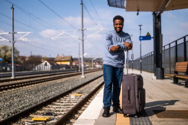 Tren istasyonunda duran bavullu mutlu adam..