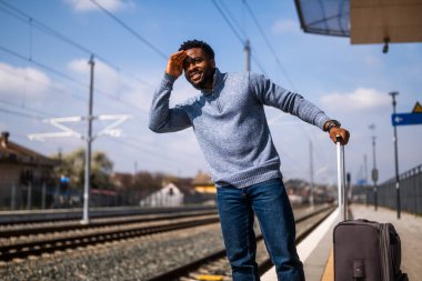 Tren istasyonunda dikilirken mutlu adam bakışlarını kaçırıyor..