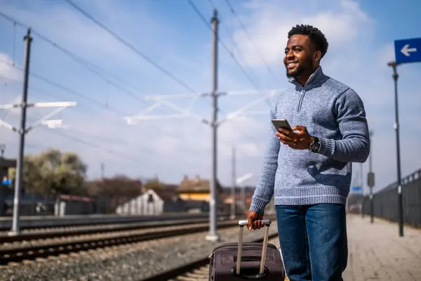 Homem Feliz Com Uma Mala Usando Telefone Enquanto Estava Estação — Fotografia de Stock