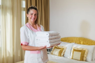 Elinde temiz ve temiz havlular tutan güzel otel hizmetçisinin portresi..