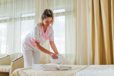 Güzel otel hizmetçisi odadaki temiz ve temiz havluları koyuyor..