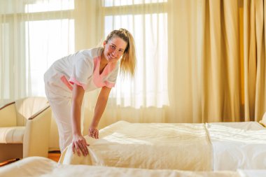 Güzel otel hizmetçisi bir odada yatak yapıyor..