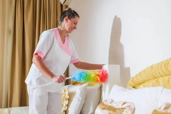 Hübsches Hotelmädchen Putzt Zimmer Mit Staubwedel lizenzfreie Stockbilder