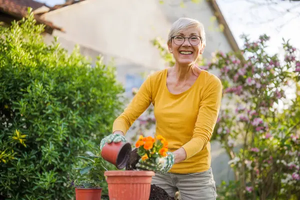 庭でガーデニングするハッピーな女性 彼女は花を植えている ストック写真