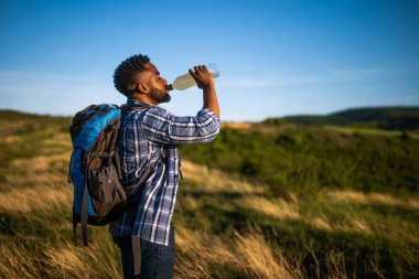 Genç adam yürüyüş yapmayı ve enerji içeceği içmeyi seviyor..