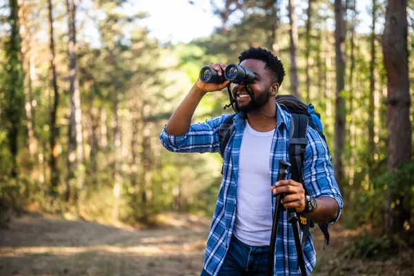 Young Man Enjoys Using Binoculars Hiking Nature Стоковая Картинка