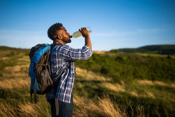 若い男はハイキングを楽しんで エネルギードリンクを飲む ロイヤリティフリーのストック写真