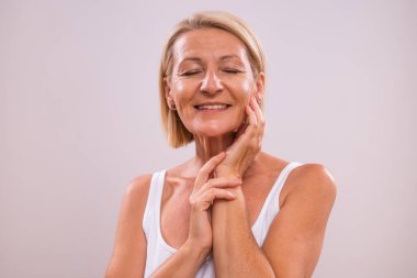 Gri arka planda güzel olgun bir kadının portresi. Güzellik konsepti.