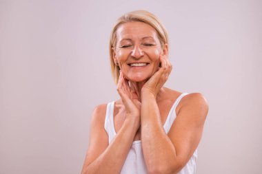 Gri arka planda güzel olgun bir kadının portresi. Güzellik konsepti.