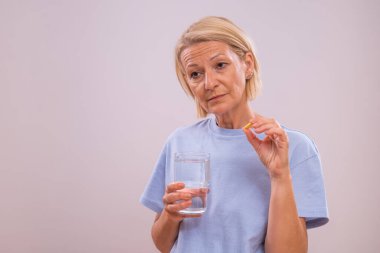 Endişeli olgun kadın hap alıyor..