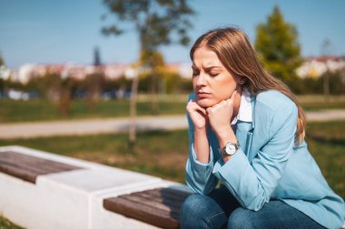 Depresyonda ve bitkin bir iş kadını bankta oturuyor..