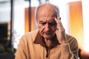 Şehir barında otururken başı ağrıyan ve bir şeyler düşünen üzgün yaşlı adamın portresini kapat..