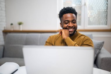 Mutlu bir Afro-Amerikalının bilgisayarı kullanırken ve ofisinden çalışırken çekilmiş fotoğrafı..