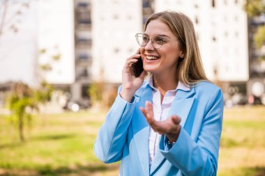 Başarılı bayan girişimci şehir parkındaki cep telefonunda iş detaylarını tartışır..