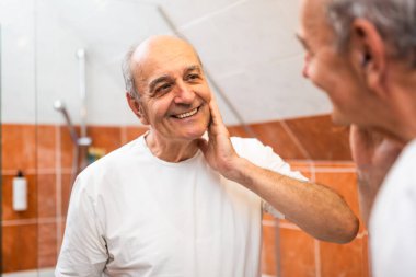 Banyo aynasında kendine bakan kırışıklıkları ve yeni bir teni olan kendinden emin son sınıf öğrencisi..