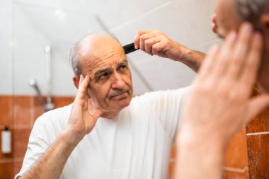 Banyoda aynanın önünde saçını tararken son sınıf öğrencisinin canı sıkkın. Saç dökülmesi konsepti.