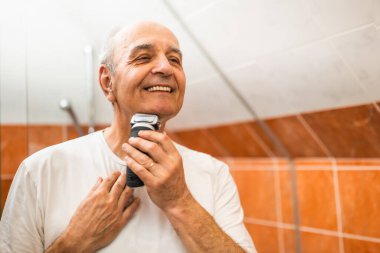 Banyoda tıraş olurken sakalını tıraş ederken yansımasına gülümseyen son sınıf öğrencisinin portresi..