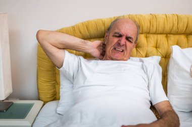 Kıdemli adamın sabah uyandıktan sonra evinde yatarken boynu ağrıdığı için memnun değil..