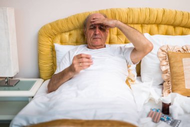 Son sınıf öğrencisi hasta yatağında yatıp ateşini ölçüyor ve nezle virüsü ya da gribi düşünüyor..