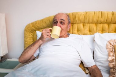 Rahatlamış son sınıf öğrencisi sabah kahvesini içerken yatakta kaygısız ve ferahlatıcı günün tadını çıkarıyor..