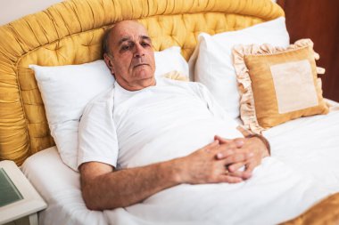  Yaşlı adam yatakta tek başına yatıyor ve depresyon ve yalnızlıkla baş ediyor..